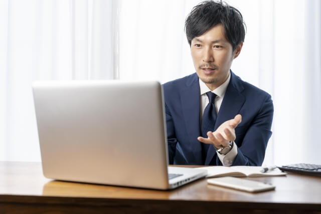 ノートパソコンを使うスーツの男性