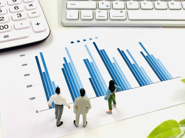 グラフを分析する小さなビジネスマン